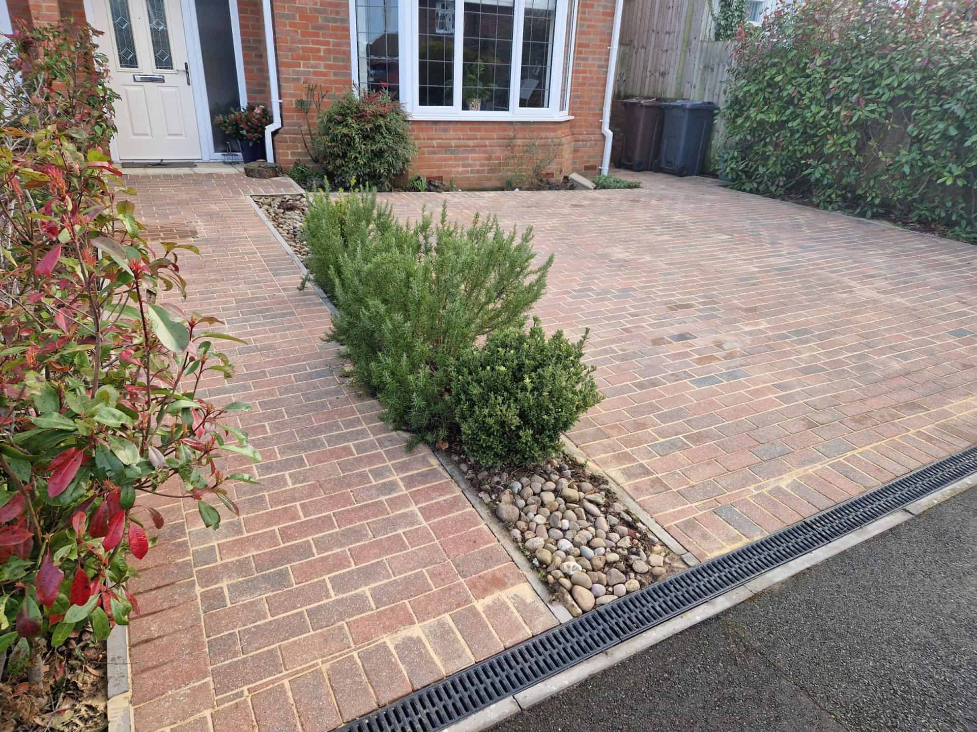 Finished block-paved driveway after cleaning, the paving back to its original colour beside the front garden shrubs