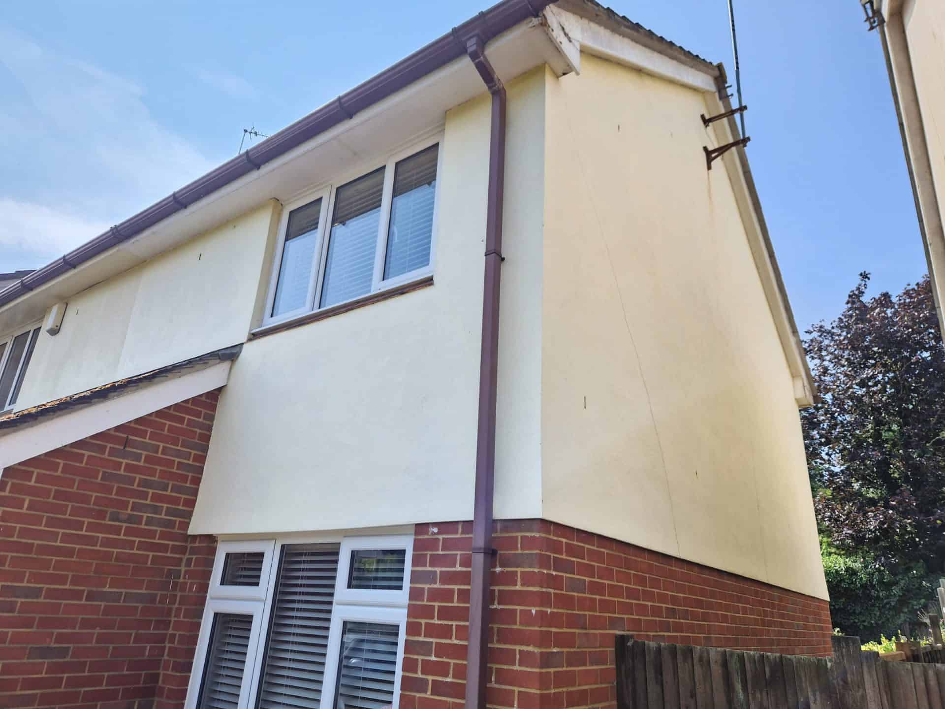House with cream render above exposed brickwork after cleaning, showing the two surfaces together