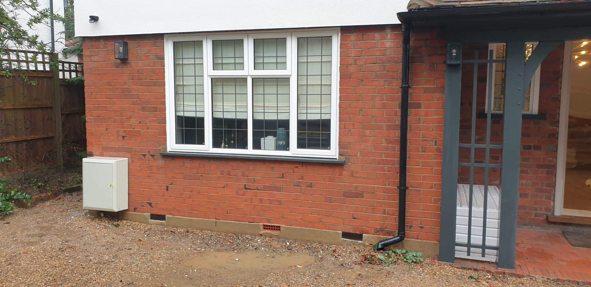The same brick house elevation after cleaning, the algae gone and the red brick colour restored