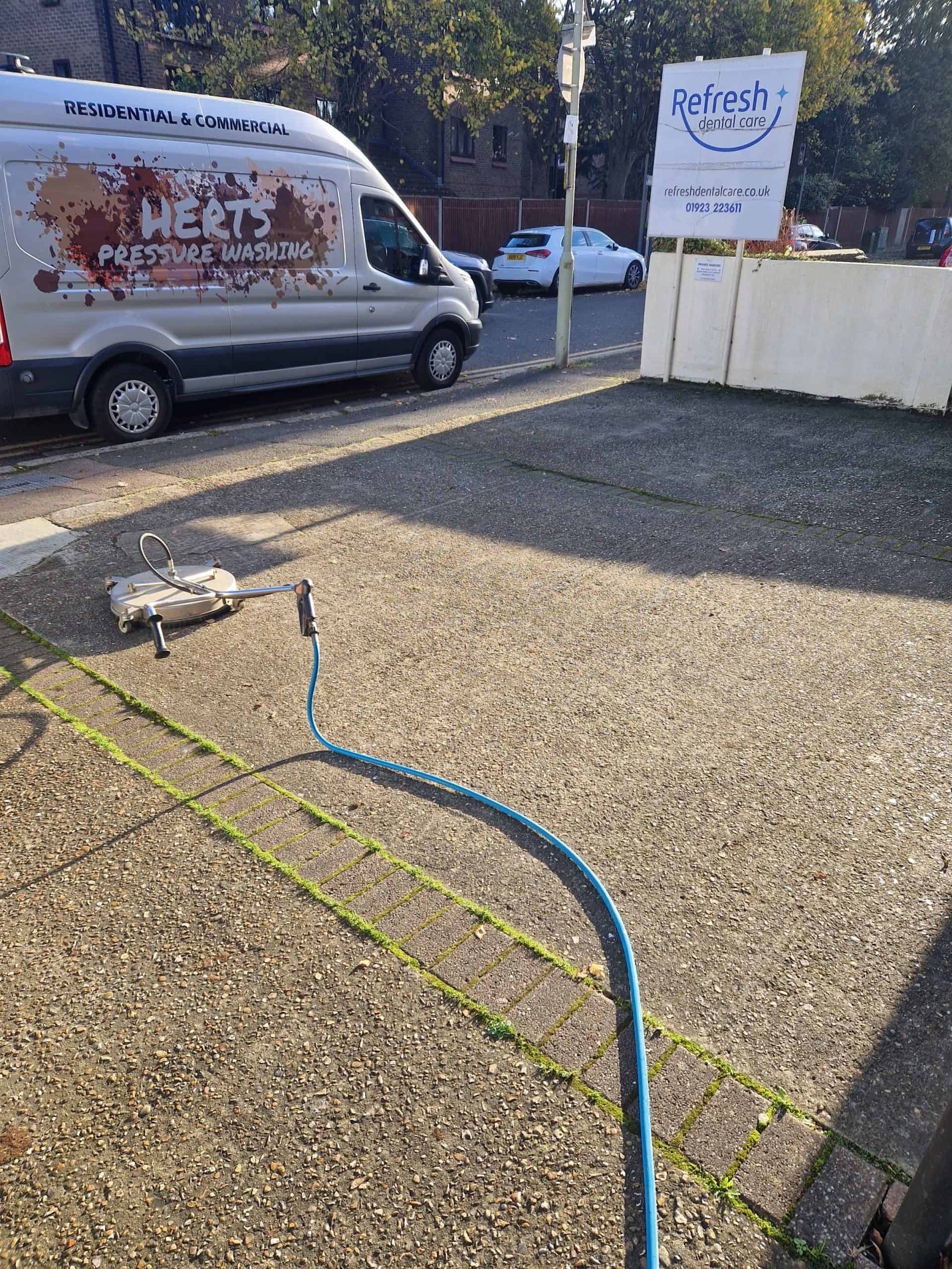Block-paved dental practice car park being pressure washed, oil and grime lifted from the bays