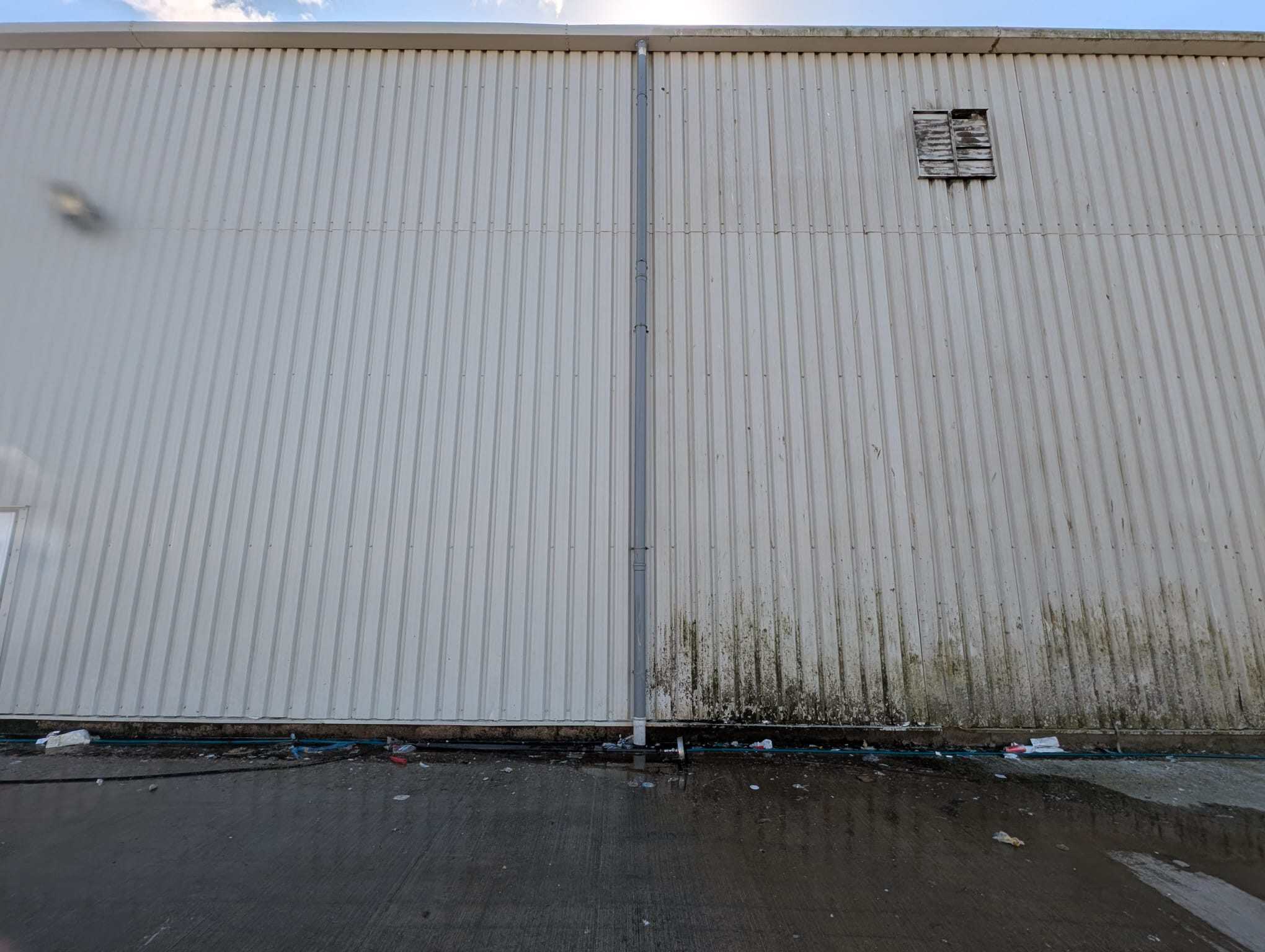 Warehouse cladding panels before and after cleaning, the cleaned section beside the dirty one