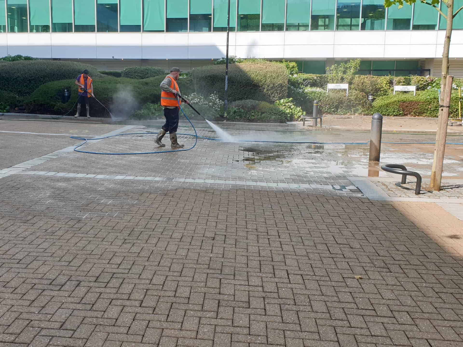 Commercial block paving being pressure washed outside an office