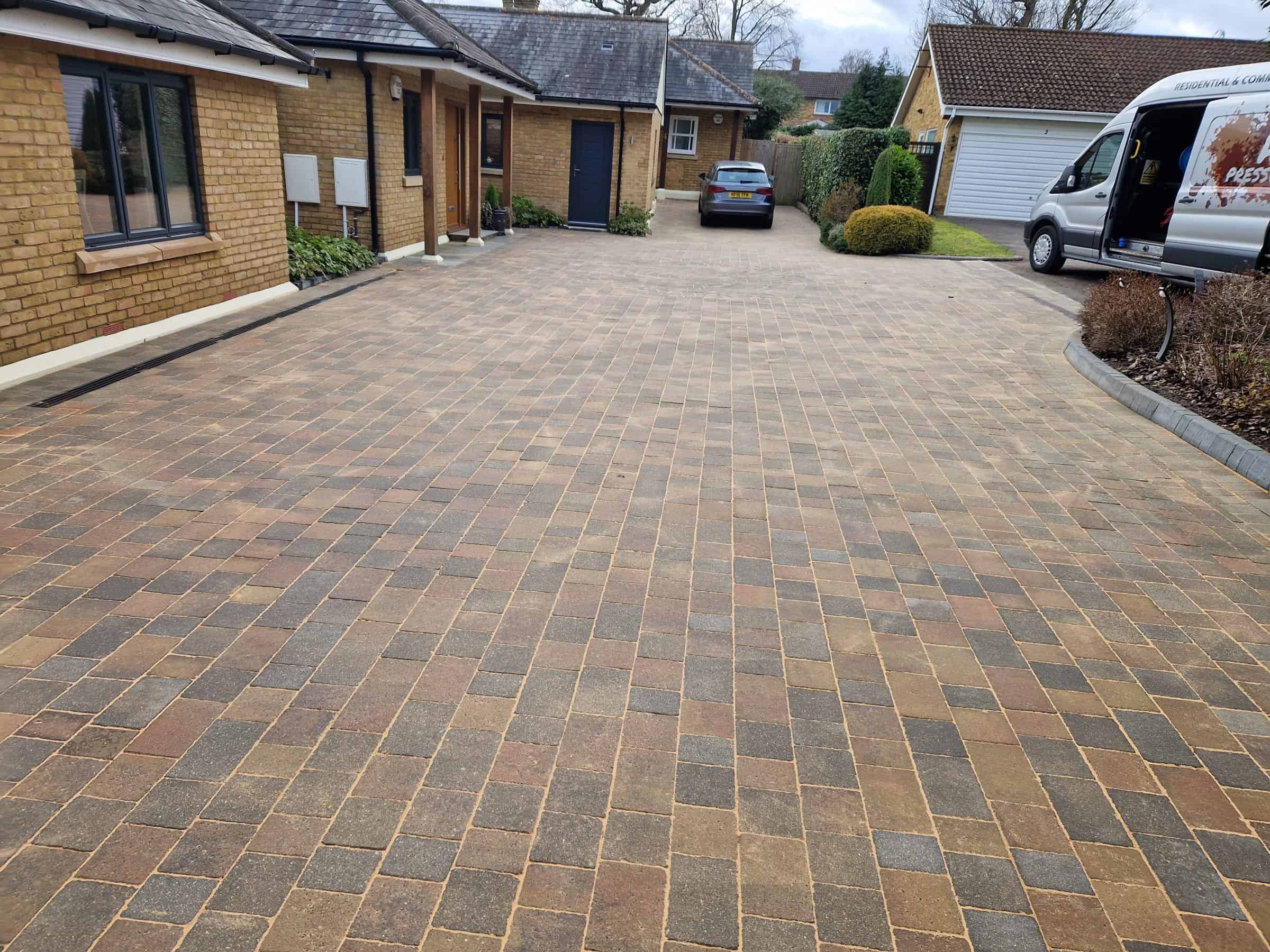 Cleaned block-paved driveway with the Herts Pressure Washing van parked on it