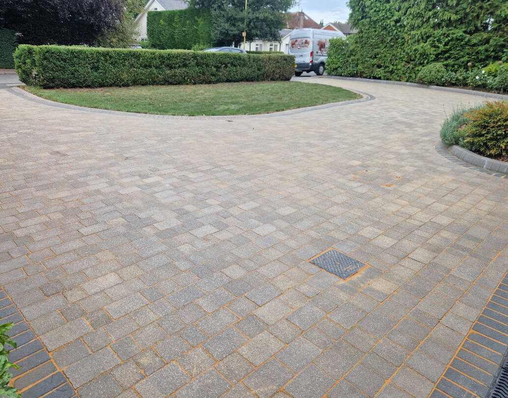 Clean grey block paving driveway with charcoal border around a lawn island in Hertfordshire, Herts Pressure Washing van on site