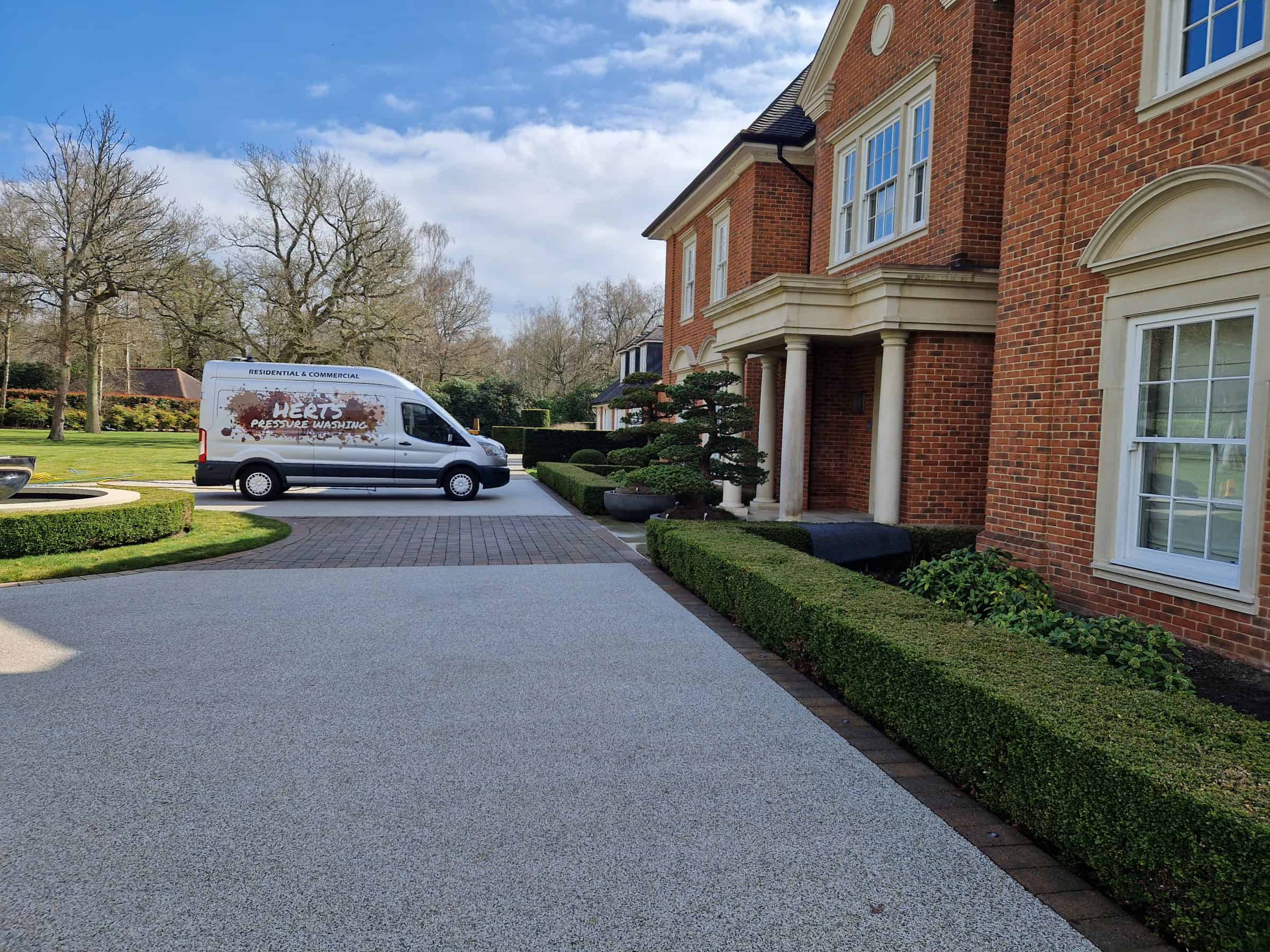 The Herts Pressure Washing van parked on a freshly cleaned resin-bound driveway