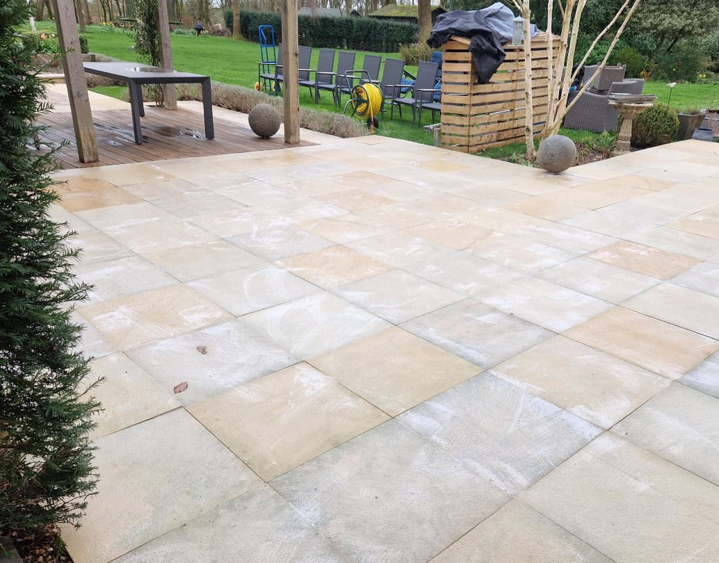Cleaned sandstone patio next to timber decking in a Hertfordshire garden, after professional patio cleaning