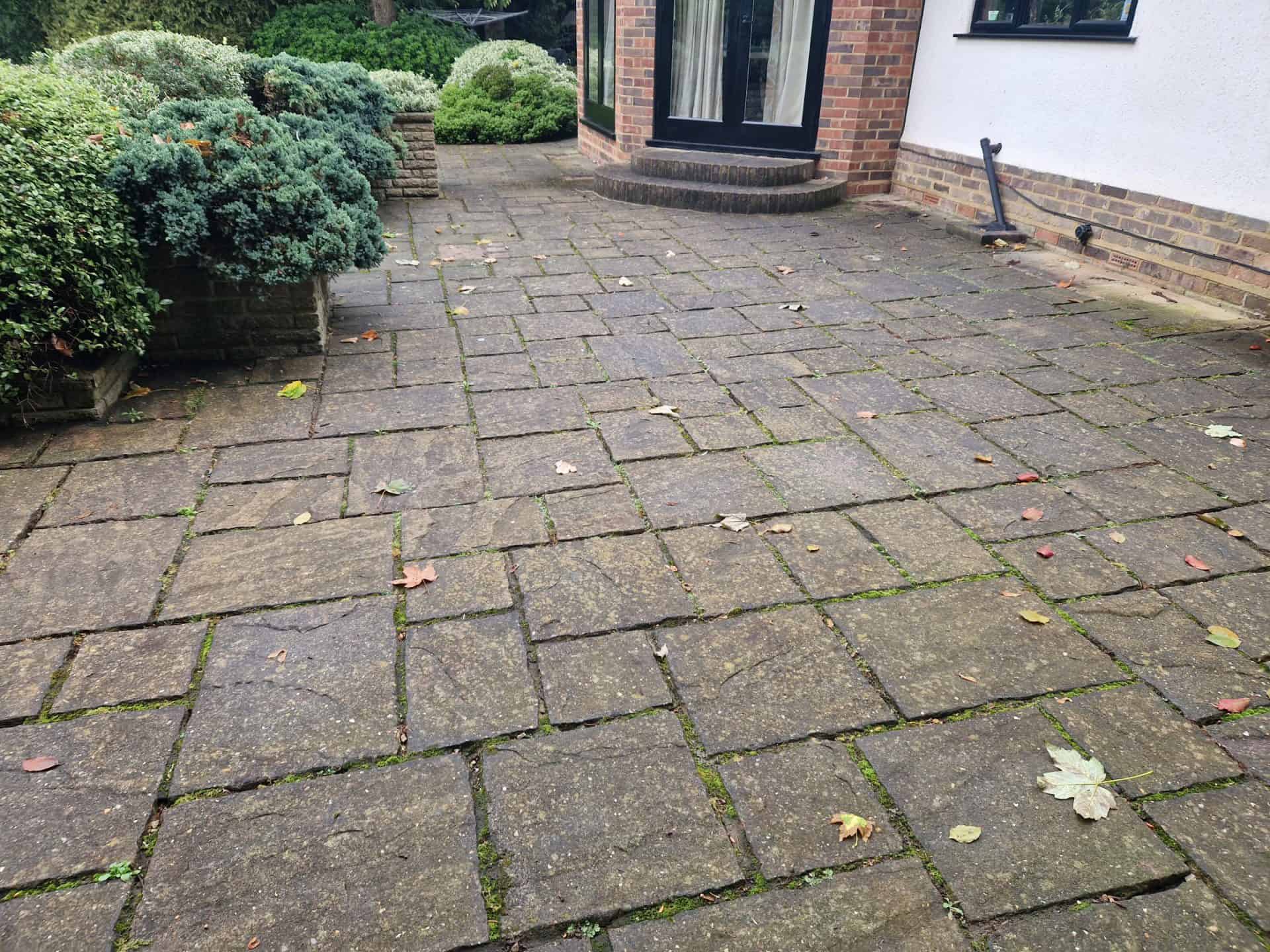 Patio in Radlett with failed cement pointing, gaps and loose mortar between the slabs before repointing
