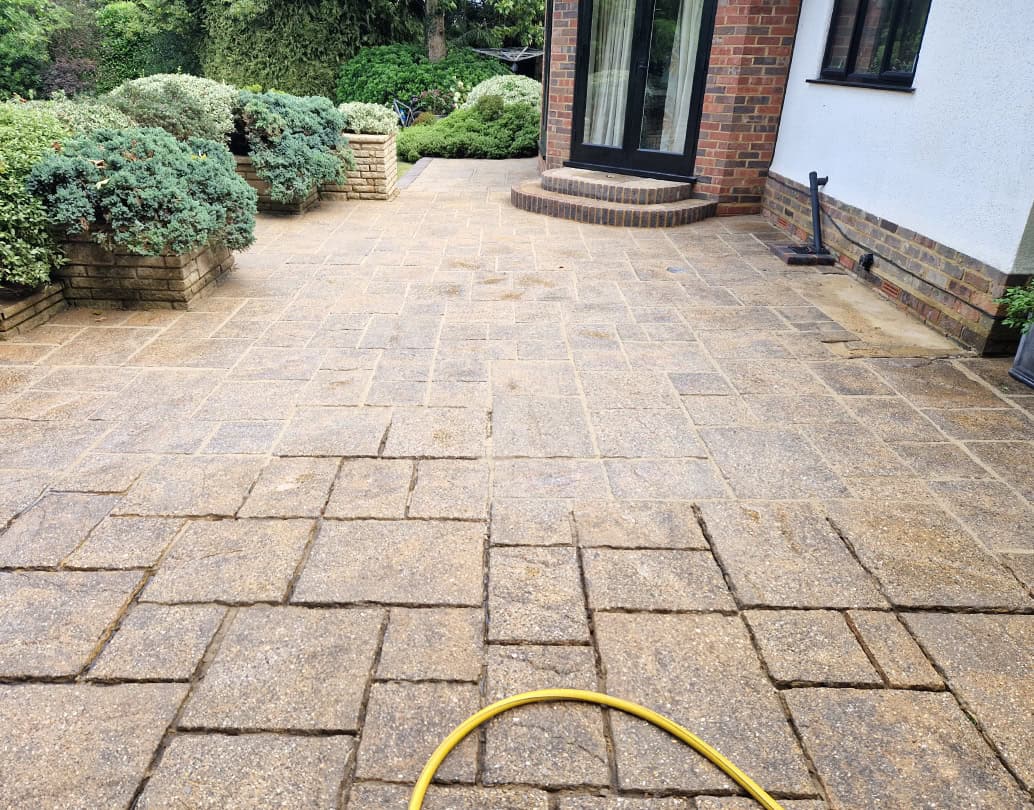 Cleaned brindle patio slabs by a brick step in a Hertfordshire garden, during professional patio repointing