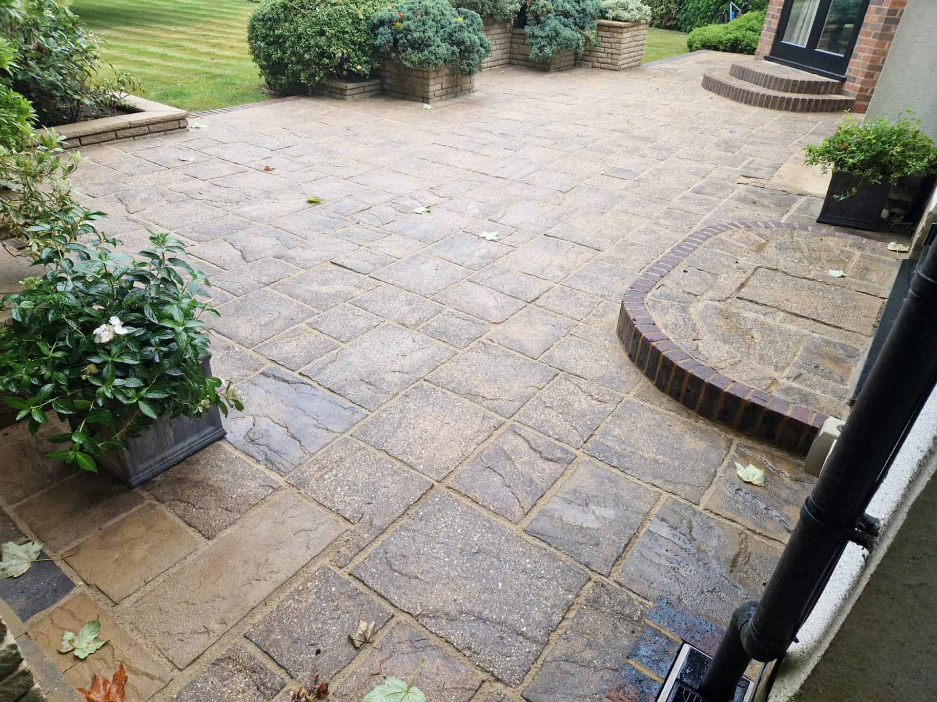 Paving, step and brick edging in Radlett after cleaning and repointing, with planters and lawn beyond