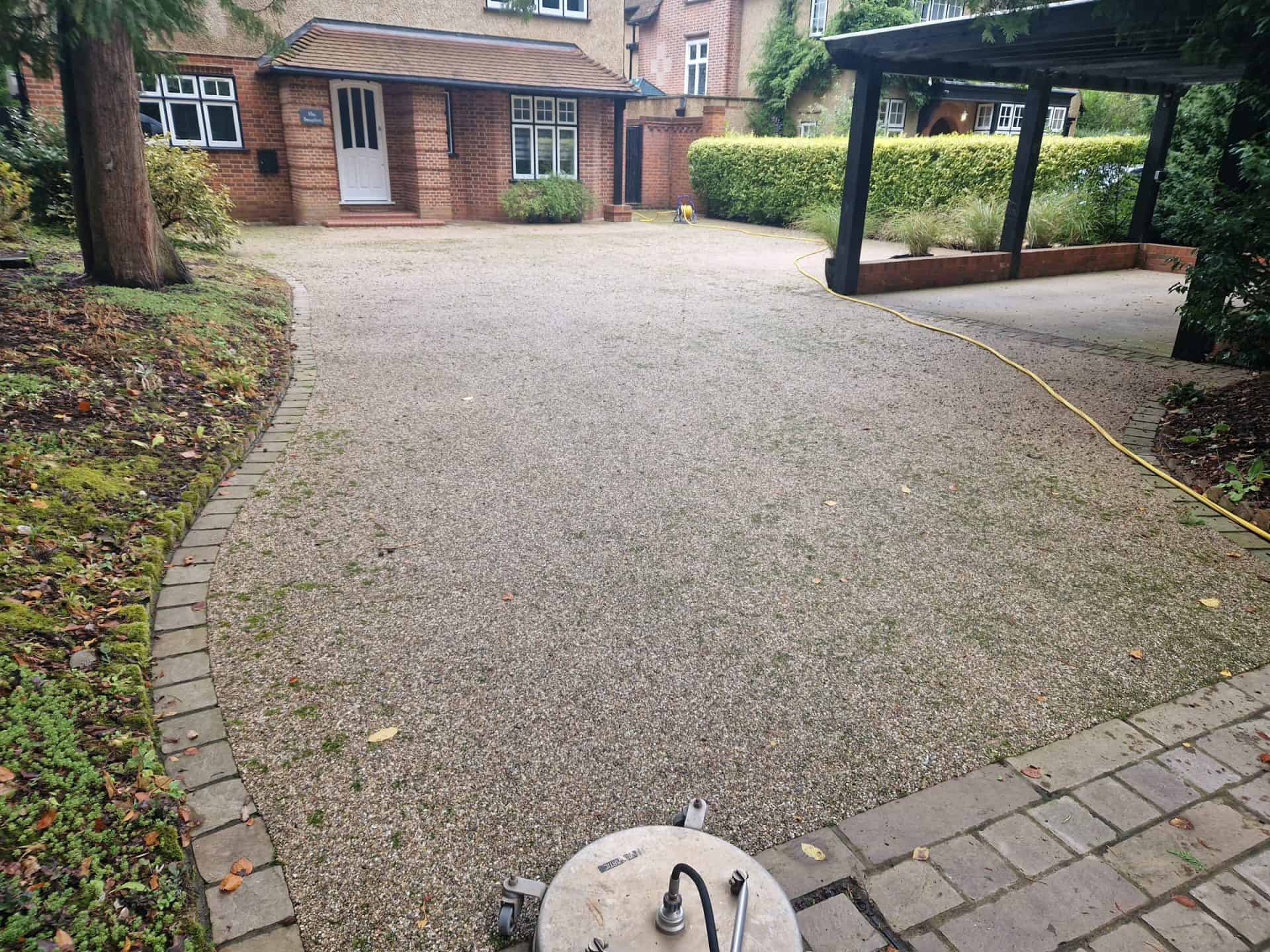 Resin-bound driveway before cleaning, the aggregate dulled by dirt, with the rotary surface cleaner set up ready to start