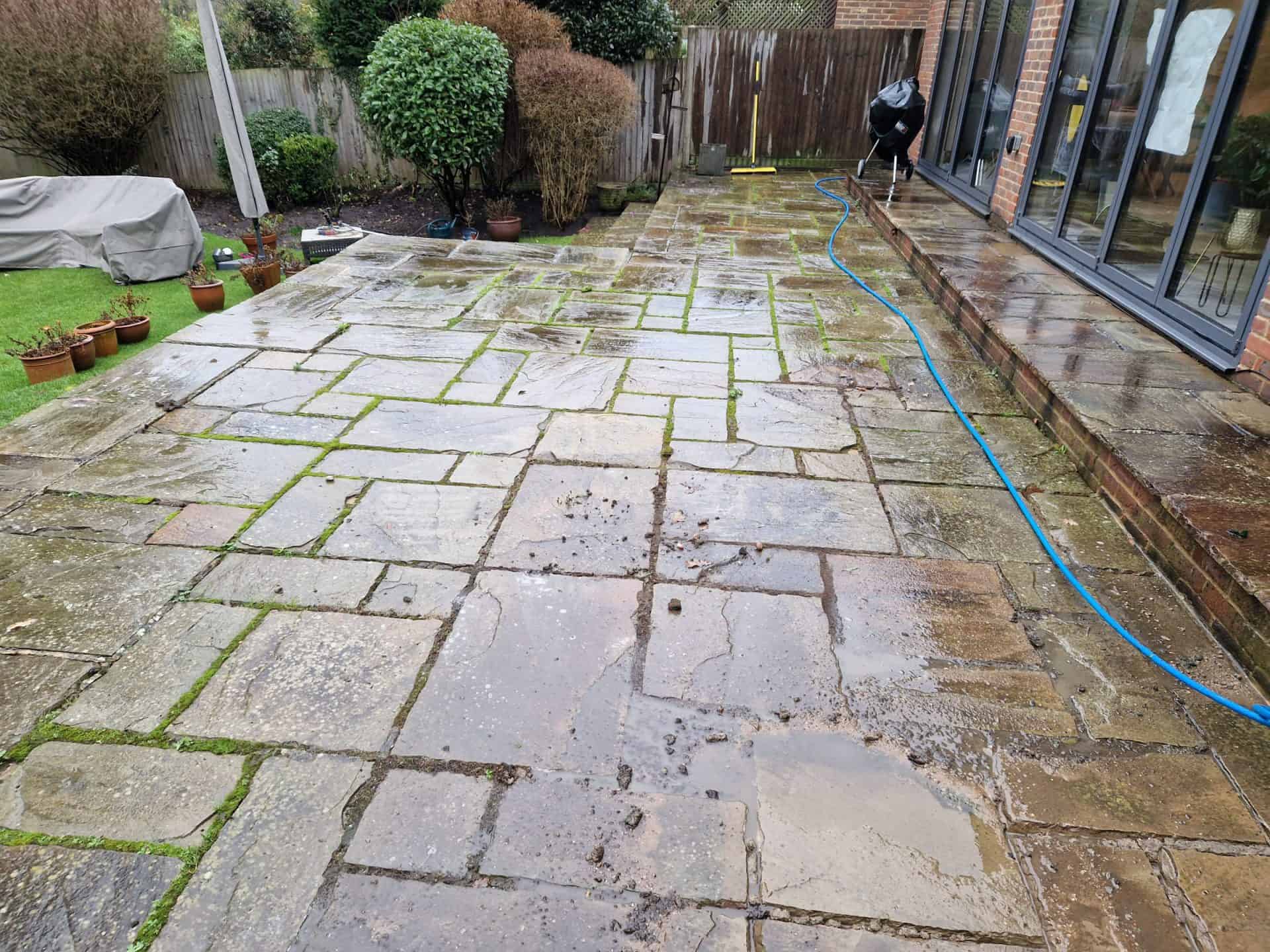 Indian sandstone patio in Radlett before cleaning, with algae and black spot across the slabs