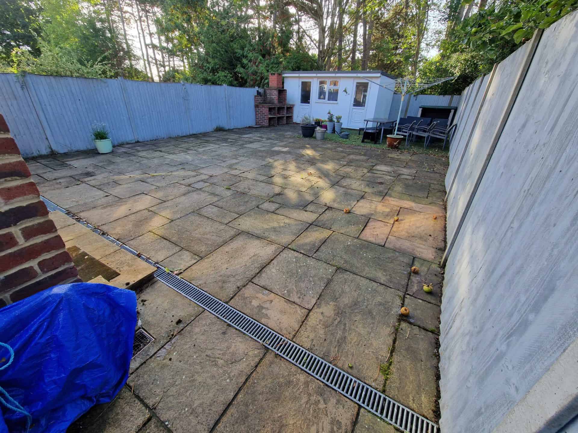 Indian sandstone patio in Borehamwood before cleaning, the slabs grey with dirt and black spot