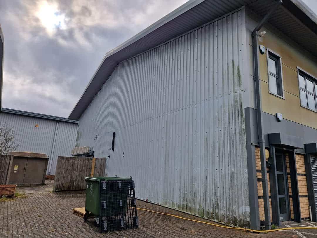 Profiled steel warehouse cladding part way through cleaning