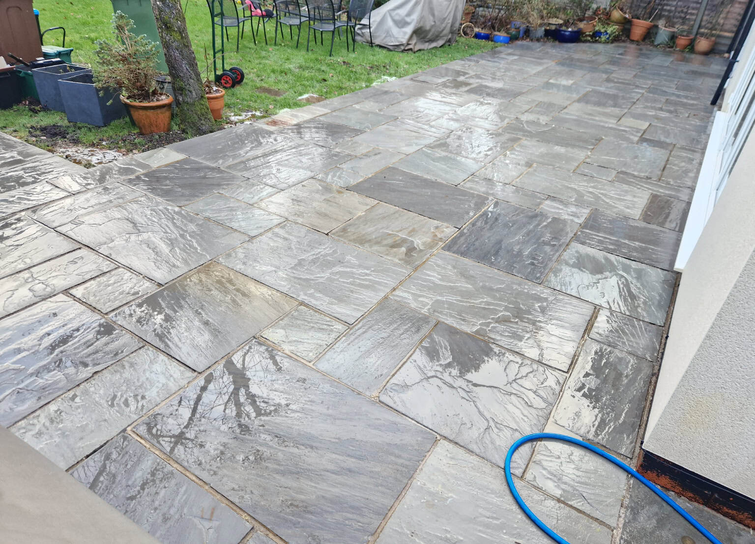 Grey sandstone patio after pressure washing, with moss and weeds removed